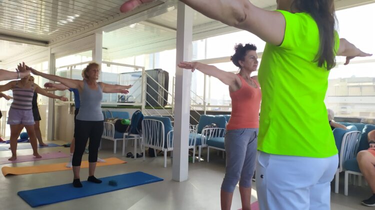 Un momento del seminario di ginnastica dello scorso anno. Simona Binci è di spalle e guida l'allenamento. Ha le braccia parallele al pavimento e indossa una maglietta verde acido e pantaloni da ginnastica grigi. Davanti a lei, i soci Uici si allenano sui tappetini
