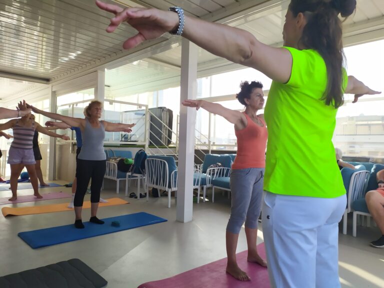 Un momento del seminario di ginnastica dello scorso anno. Simona Binci è di spalle e guida l'allenamento. Ha le braccia parallele al pavimento e indossa una maglietta verde acido e pantaloni da ginnastica grigi. Davanti a lei, i soci Uici si allenano sui tappetini