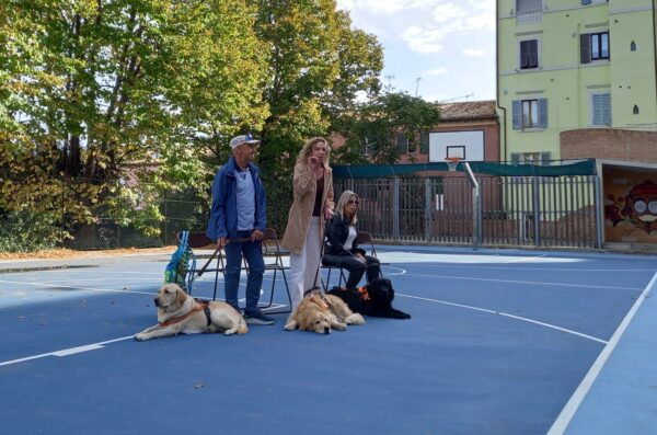 Stefania, Mario e Claudia nel piazzale della scuola fanno lezione ai bambini insieme ai loro bellissimi cani guida