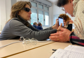 Nella foto un momento di una lezione di tecnologia assistiva. In primo piano, sedute a una scrivania, la presidente Uici di Ascoli, Gigliola Chiappini, mostra la schermata di cellulare a una socia