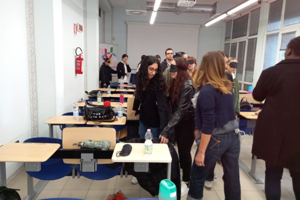 L'interno di un'aula in cui si è tenuta la lezione. Alcune studentesse sono bendate e provano a muoversi accompagnate dai compagni di studio