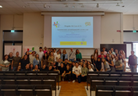 Una bella foto di gruppo all'interno della grande aula dell'università. In primo piano i banchi, in fondo, davanti alla scrivania, gli studenti, gli insegnanti e i dirigente Uici posano sorridenti