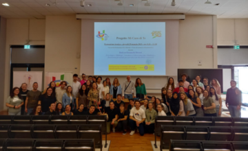 Una bella foto di gruppo all'interno della grande aula dell'università. In primo piano i banchi, in fondo, davanti alla scrivania, gli studenti, gli insegnanti e i dirigente Uici posano sorridenti
