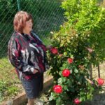 La presidente Uici Macerata, Bruna Giampieri sorridente accanto a un cespuglio di rose