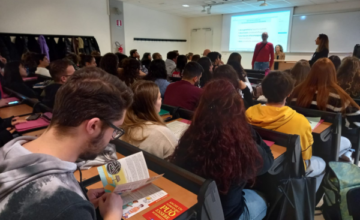 Una immagine dall'aula gremita nella lezione odierna. I ragazzi, di spalle, seguono la lezione. Sul tavolo dei relatori, Andrea Cionna, Stefania Terrè ed Emanuela Storani