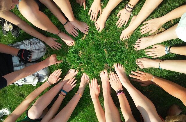mani e piedi nudi di ragazzi e ragazze in cerchio su un prato verde